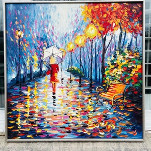 May include: A painting of a woman walking in a park with an umbrella. The woman is wearing a red coat and the park is filled with colorful trees and a bench. The ground is wet and reflects the light from the street lamps.
