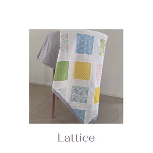 May include: A white quilt with a lattice pattern. The quilt is made of different fabrics with various patterns, including a yellow and white polka dot pattern, a green floral pattern, and a blue and white bird pattern. The quilt is folded and draped over a chair.