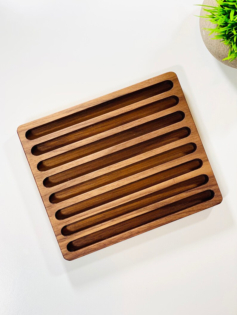 May include: A wooden tray with 10 slots for storing items. The tray is made of dark brown wood and has a rectangular shape.