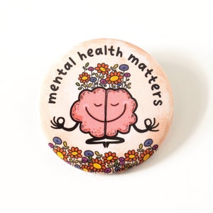 May include: A pink brain with a smiling face is meditating with flowers on its head. The text around the brain says "mental health matters".
