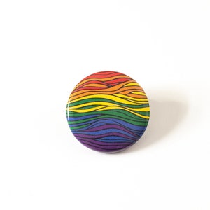 May include: A round button with a rainbow pattern of wavy lines. The button is white with a black outline.