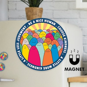 May include: A blue and white round magnet with a colourful illustration of smiling faces and the text "A little less judgment, be a nice human. Choose kindness, a little more kindness."