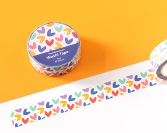 May include: Two rolls of washi tape featuring a repeating pattern of small red, yellow, purple, and teal hearts on a white background. One roll is coiled, while the other is partially unrolled, displaying the heart print and the label Washi Tape.