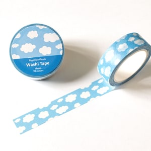 May include: A roll of blue washi tape featuring a white cloud design, with a length of tape unrolled. The tape is labelled "Washi Tape" and "clouds 10 metres". The tape is from RippleSplashStudio.