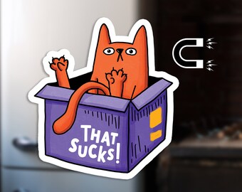 May include: A cartoon orange cat is stuck in a purple box with the text "THAT SUCKS!" on the front. A magnet is shown above the box.
