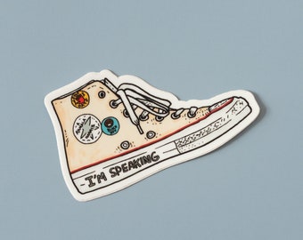 May include: A beige high-top sneaker with red stitching and a white sole. The sneaker has various patches and the text "I'm Speaking" on the side.