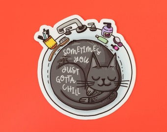 Könnte beinhalten: Eine schwarze Katze mit geschlossenen Augen schläft in einer weißen Badewanne mit dem Text "Sometimes you just gotta chill" auf der Seite. Die Badewanne ist gefüllt mit verschiedenen Toilettenartikeln, darunter eine Zahnbürste, eine Flasche Lotion und eine Flasche Nagellack.