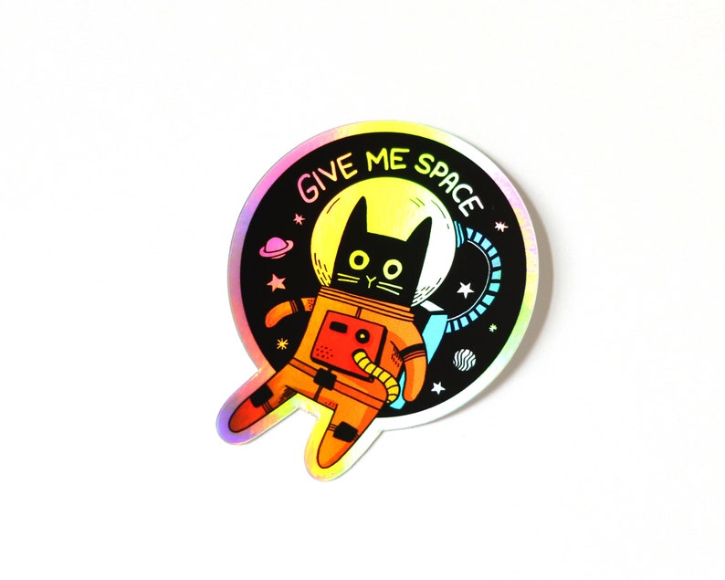 May include: A black cat wearing an orange spacesuit with the text "Give Me Space" in a rainbow holographic circle.