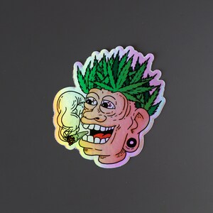 Peut inclure: Autocollant holographique repr&eacute;sentant un personnage de dessin anim&eacute; avec des cheveux en forme de feuilles de cannabis vertes, un large sourire et des yeux rouges, exhalant de la fum&eacute;e. Le personnage fume un joint. Finition iris&eacute;e.