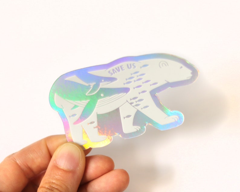 May include: A holographic sticker featuring a polar bear carrying a whale and a smaller dolphin. The sticker has the text "SAVE US" and a school of fish swimming around the animals.
