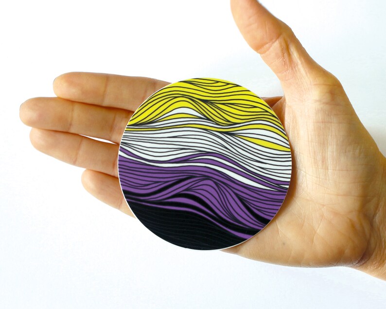 May include: A round sticker with a wavy design in yellow, white, purple, and black colors.