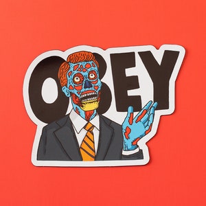 May include: A sticker with a black and white graphic of the word "OBEY" and a cartoon image of a man with a blue and red face wearing a suit and tie. The man is holding out his right hand.