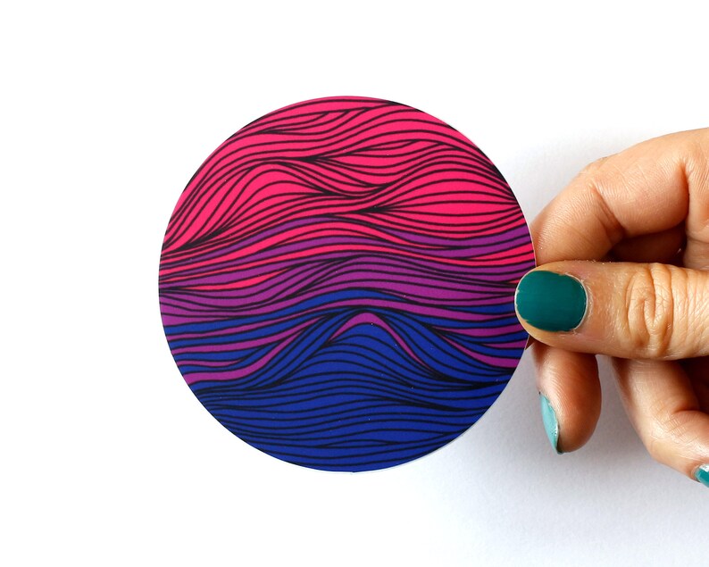 May include: A round sticker with a wavy pattern in shades of pink, purple, and blue. The waves are layered and create a gradient effect.