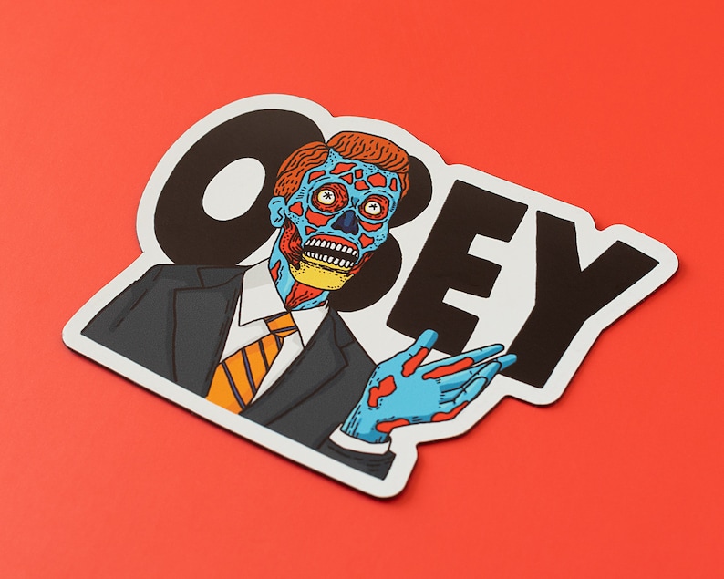 May include: A black and white sticker with the word "OBEY" in large, bold letters. A cartoon image of a man with blue and red skin, wearing a suit and tie, is partially visible behind the word "OBEY".
