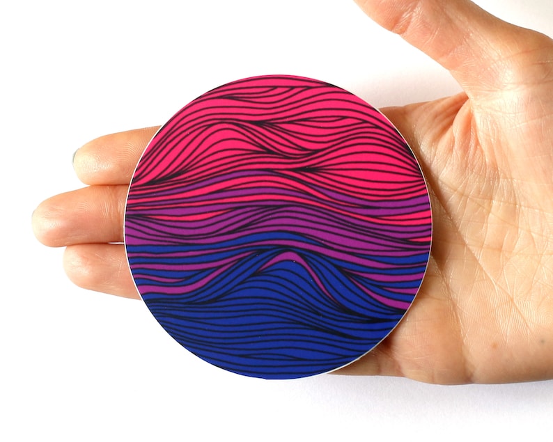 May include: A round sticker with a wavy, abstract design in pink, purple, and blue colors. The sticker is in the shape of a circle and has a glossy finish.