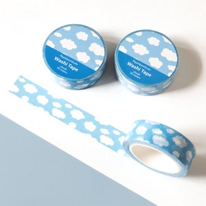 May include: Two rolls of blue washi tape with a white cloud pattern, and a strip of tape unrolled. The tape rolls have the text "Washi Tape" and "clouds 10 meters". The background is white and light blue.