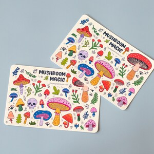May include: Two colorful sticker sheets with a mushroom theme. The stickers feature various types of mushrooms, skulls, and foliage in a whimsical style. The text "Mushroom Magic" is printed on each sheet.