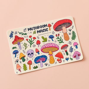 May include: A sticker featuring a colorful illustration of various mushrooms, leaves, and a skull. The text "Mushroom Magic" and the website "RippleSplashStudio.com" are also included.