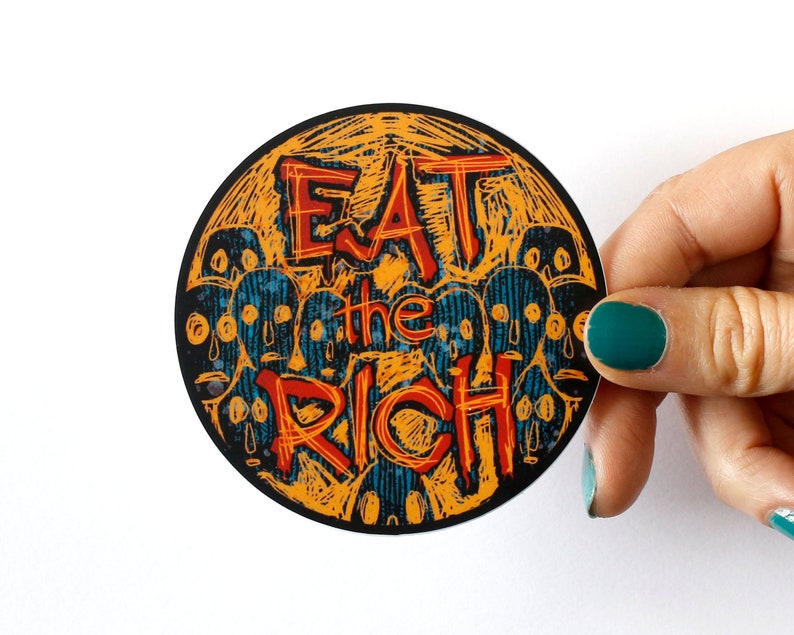 May include: A round sticker with a yellow and orange background and black and blue outlines. The sticker features the text "Eat the Rich" in red and black lettering. The background is filled with stylized faces.