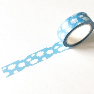 May include: A roll of blue washi tape with a repeating pattern of white clouds. The tape is partially unrolled, revealing the cloud design. The tape is on a white background.