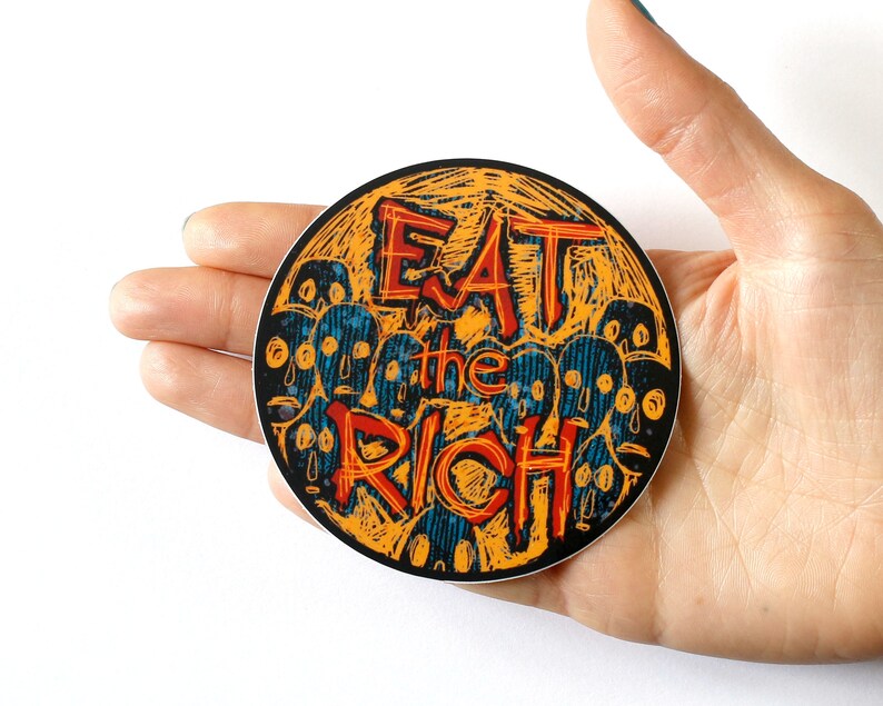 May include: A round sticker with a yellow background and black outline. The sticker features a stylized illustration of a crowd of faces with the text "Eat the Rich" in red and black lettering.