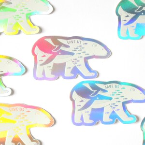 May include: A set of nine iridescent holographic stickers featuring a polar bear with a whale on its back. The stickers have the text "Save Us" and a school of fish swimming around the animals.