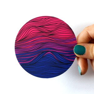 May include: A round sticker with a wavy pattern in shades of pink, purple, and blue. The sticker is designed to represent the bisexual pride flag.