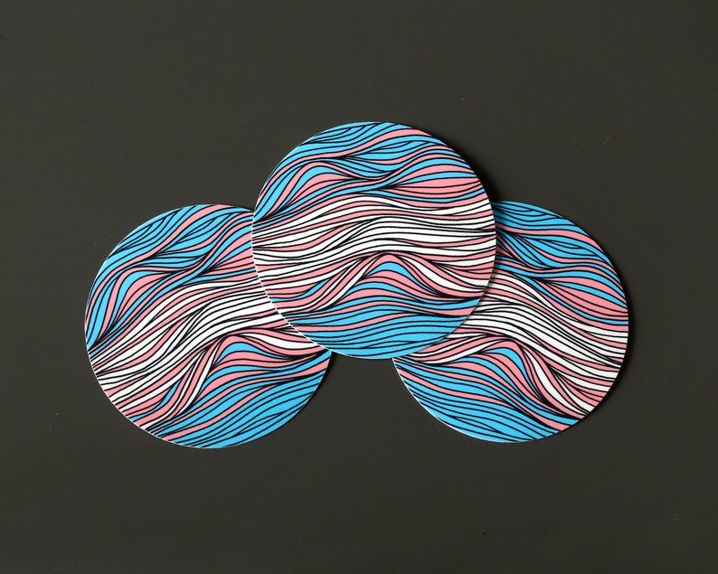 May include: Three round coasters with a wavy, abstract design in shades of blue, pink, and white.