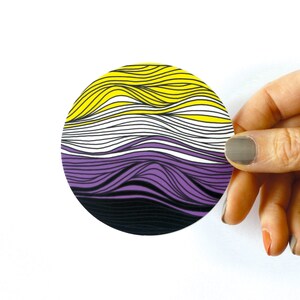 May include: A round sticker with a wavy design in yellow, white, purple, and black colors.