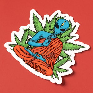 May include: A blue alien meditating in a lotus position, wearing an orange robe, surrounded by green marijuana leaves.