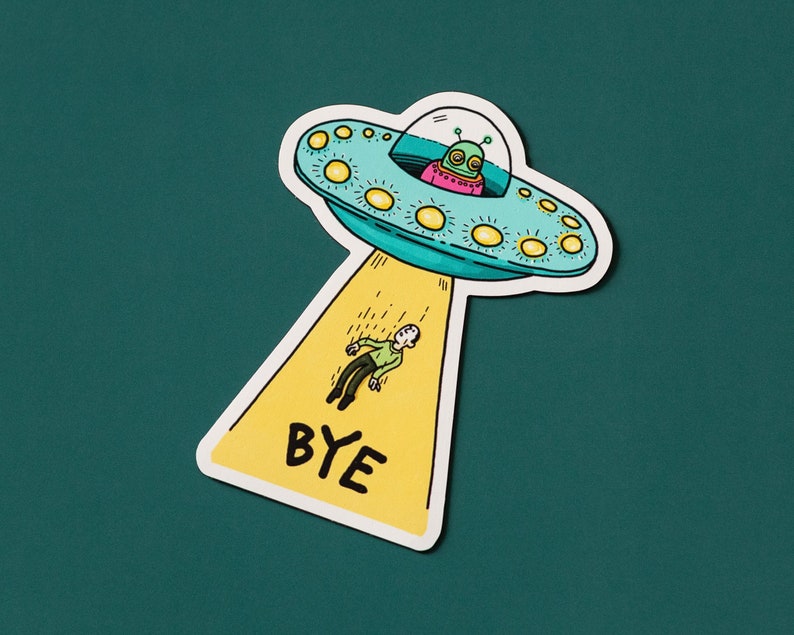 May include: A yellow and white sticker with a cartoon illustration of a flying saucer with a green alien inside. The saucer is leaving a trail of yellow stars and the text "BYE" is written below the saucer.