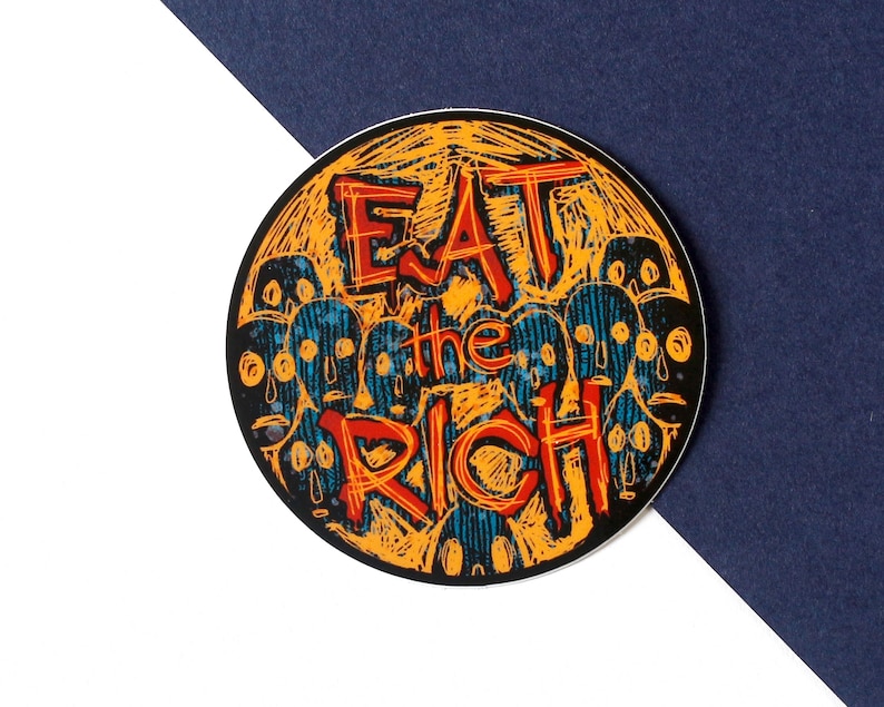 May include: A round sticker with a yellow and orange background and blue and black text. The text says "Eat the Rich" in a stylized font.