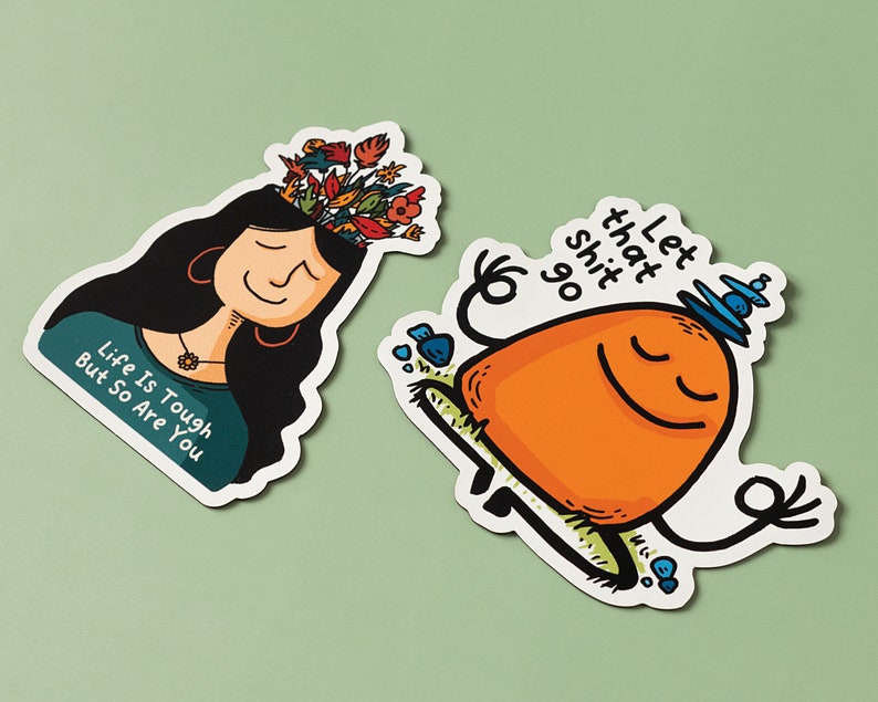 May include: Two colorful stickers with motivational messages. The first sticker features a woman with flowers growing out of her head and the text "Life is tough but so are you". The second sticker features a cartoon orange character meditating with the text "Let that shit go".