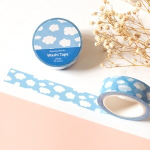 May include: Two rolls of washi tape with a blue sky and white cloud pattern. One roll is unrolled, showing the pattern. The text on the roll reads "RippleSplashStudio Washi Tape clouds 10 meters."
