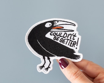 May include: White embroidered patch with a black bird with an open beak and the text "couldn't be better!" in black lettering.