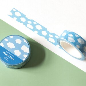 May include: Two rolls of washi tape with a sky-blue background and white cloud pattern. One roll is unrolled, revealing the tape's design. The text "RippleSplashStudio Washi Tape clouds 10 meters" is printed on the label.