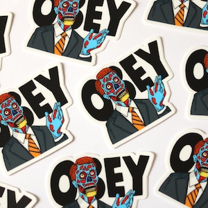 May include: A set of nine stickers featuring a cartoon character with a split face, wearing a suit and tie, with the word "OBEY" in black letters. The stickers are on a white background.