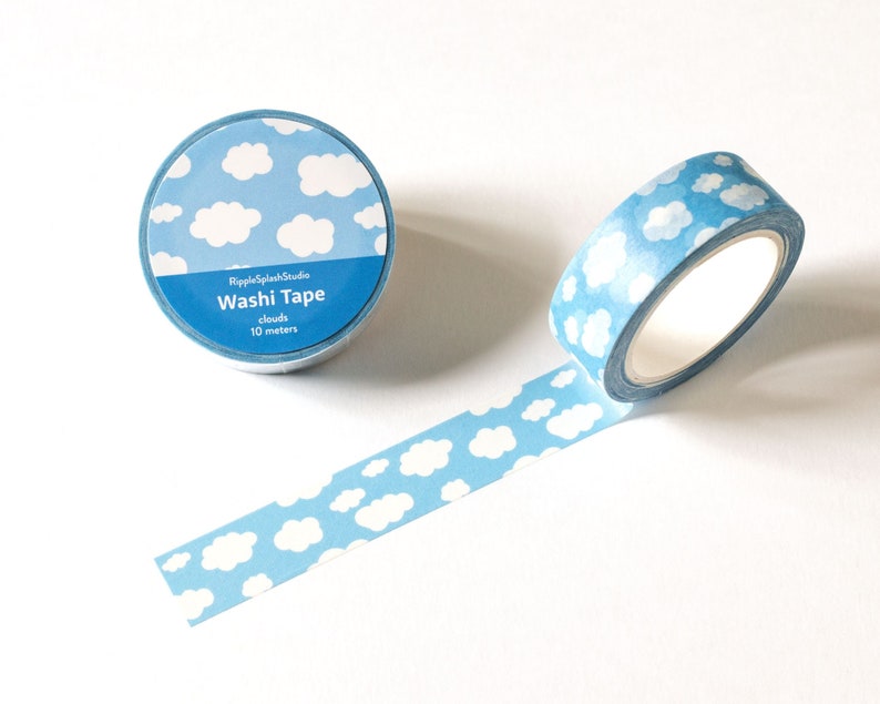 May include: A roll of blue washi tape with a cloud pattern, with a strip of tape unrolled. The tape is labeled "Washi Tape" and "clouds 10 meters". The tape is from RippleSplashStudio.