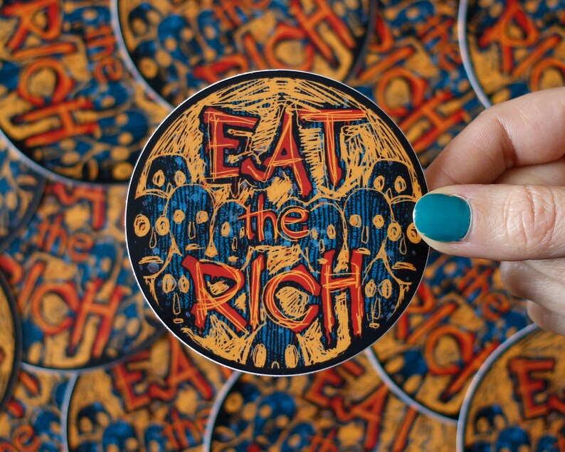 May include: A round sticker with a yellow and blue design. The sticker says "Eat the Rich" in red and black lettering.