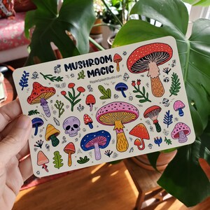 May include: A white card with a colorful illustration of mushrooms and the text "Mushroom Magic" and "RippleSplashStudio.com".