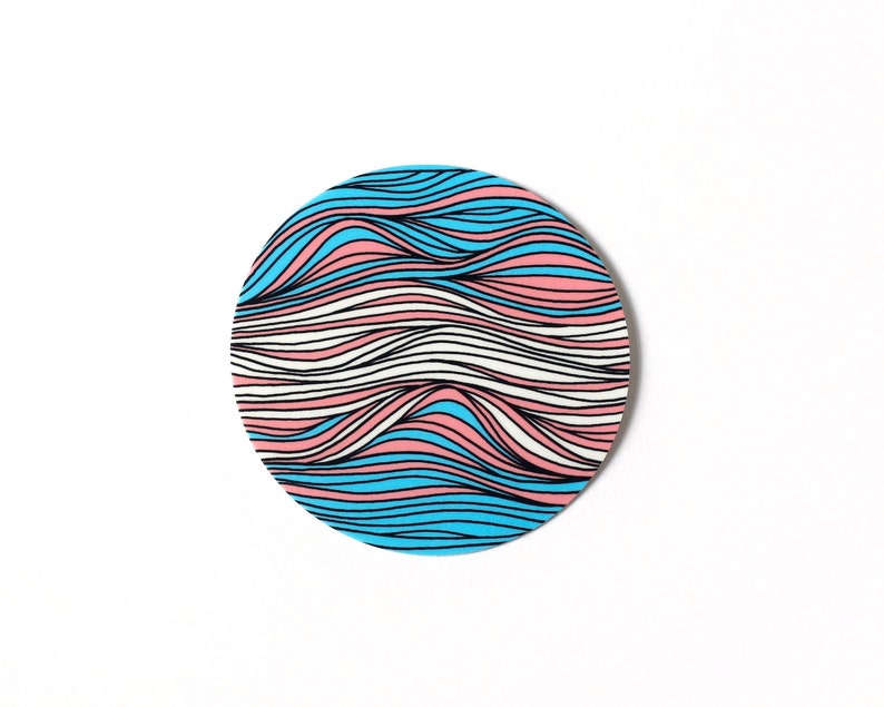 May include: A circular sticker with a wavy pattern in blue, pink, and white colors. The pattern resembles the transgender pride flag.
