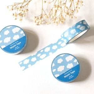 May include: Three rolls of washi tape with a blue and white cloud pattern. One roll is unrolled, showing the tape with the same cloud design. The text on the tape reads "RippleSplashStudio Washi Tape clouds 10 meters."