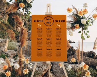 May include: A brown seating chart with the text "We Saved You A Seat" and "Jake & Milo" in a circle. The chart lists tables with names of guests.