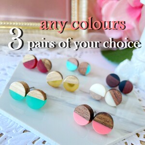 May include: A collection of wooden stud earrings in various colors, including red, teal, yellow, white, and pink. Each earring features a wooden half-circle design paired with a colored resin half-circle. Text reads: "any colours" and "3 pairs of your choice."