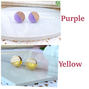May include: A pair of stud earrings with a wooden half-circle design and a purple resin half-circle. The earrings are displayed on a white surface. The word "Purple" is written in a pink font.