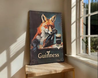 May include: A framed Guinness poster showing a fox with a pint of Guinness. The fox has orange and white fur, set against a dark backdrop. The Guinness logo is displayed below the fox in gold lettering.