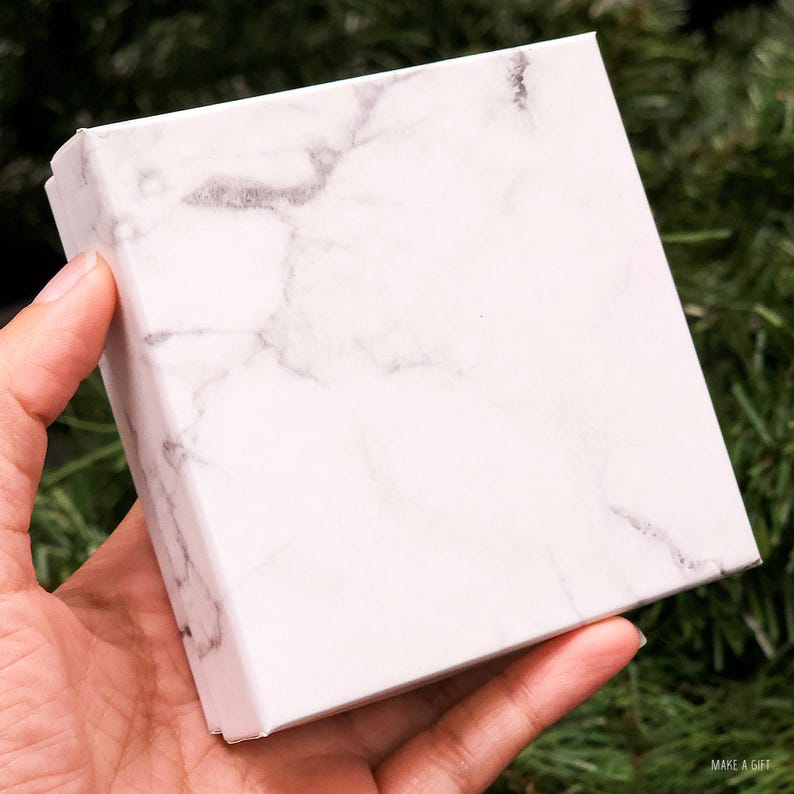 May include: A white marble gift box with a smooth, textured surface.
