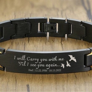May include: Black bracelet with a gold band and engraved message: "I will Carry you with me 'Til I see you again... Dad | 12.22.1956 - 10.13.2022". Three small birds are engraved on the band.