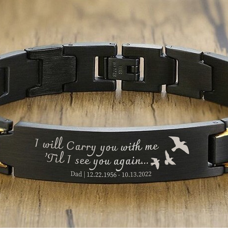 May include: Black bracelet with a gold band and engraved message: "I will Carry you with me 'Til I see you again... Dad | 12.22.1956 - 10.13.2022". Three small birds are engraved on the band.