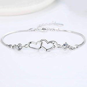 May include: A silver bracelet with two intertwined heart charms and two small clear cubic zirconia stones.